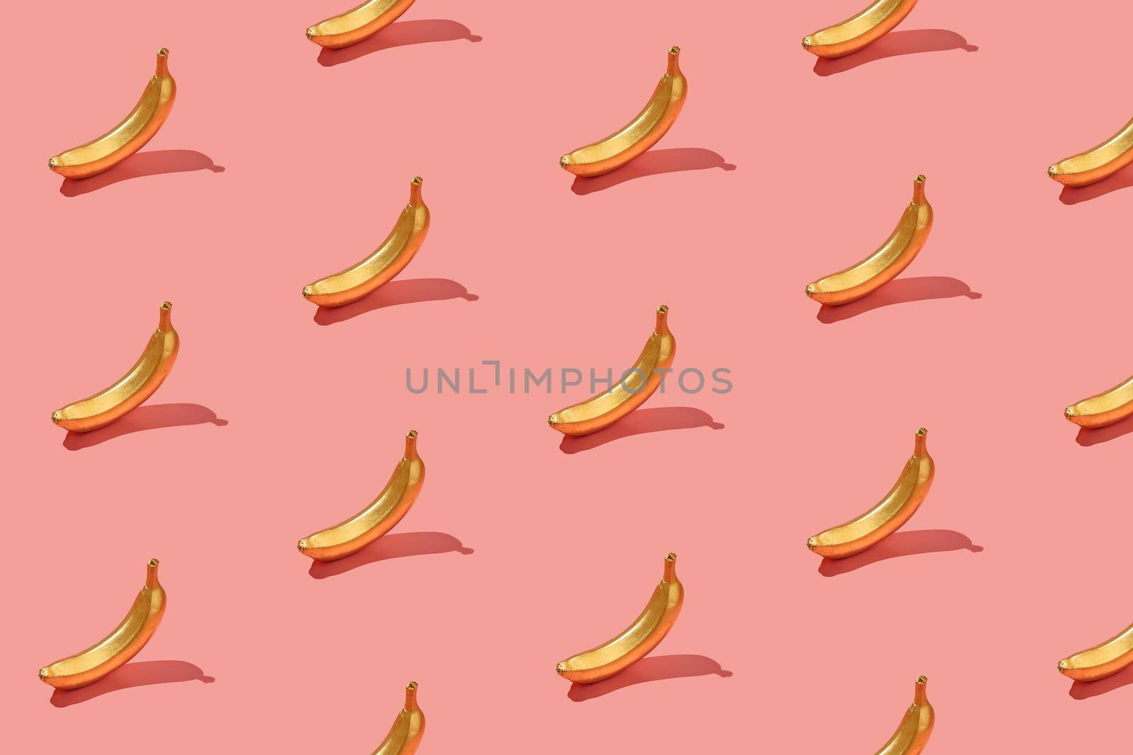 Trendy sunlight Summer pattern made with yellow banana slice on bright light pink background. Minimal summer concept.