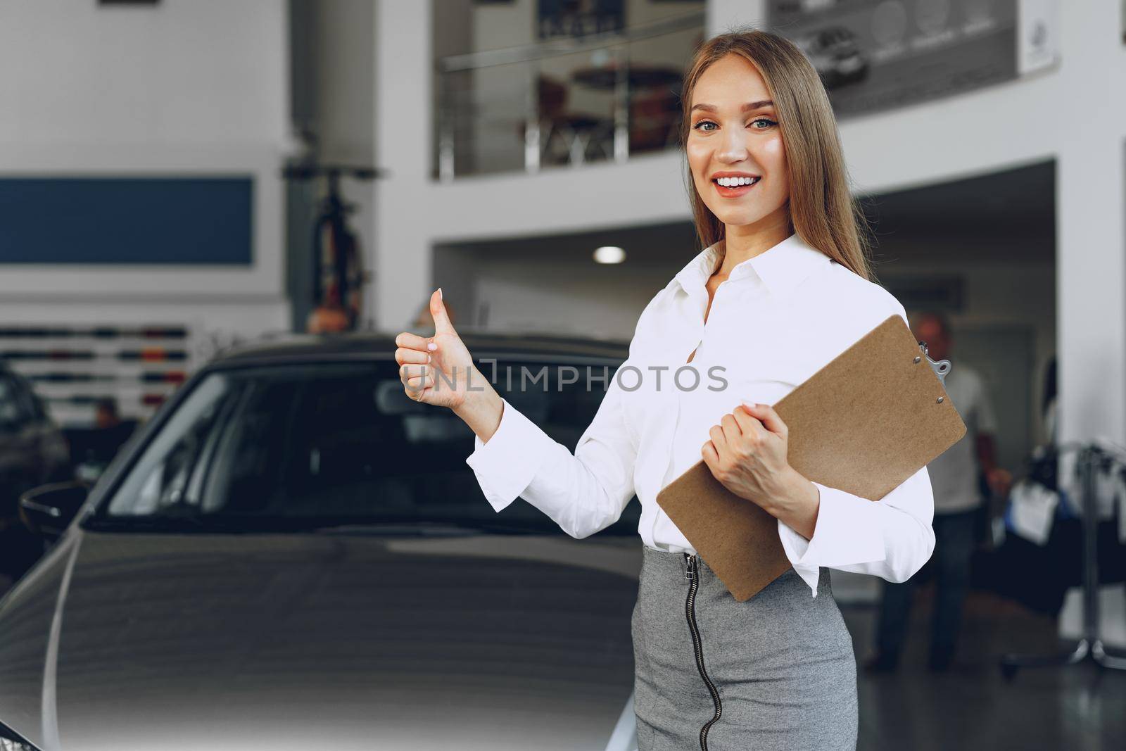 Happy beautiful young woman car dealer in showroom close up