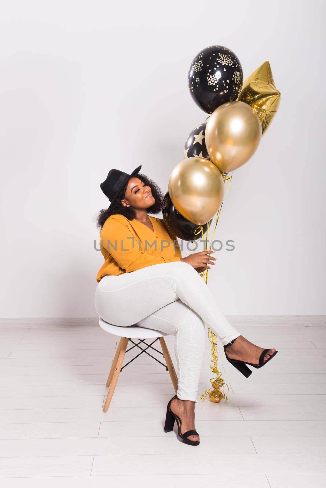 Holidays, party and fun concept - Portrait of smiling young African-American young woman looking stylish on white background with balloons. by Satura86