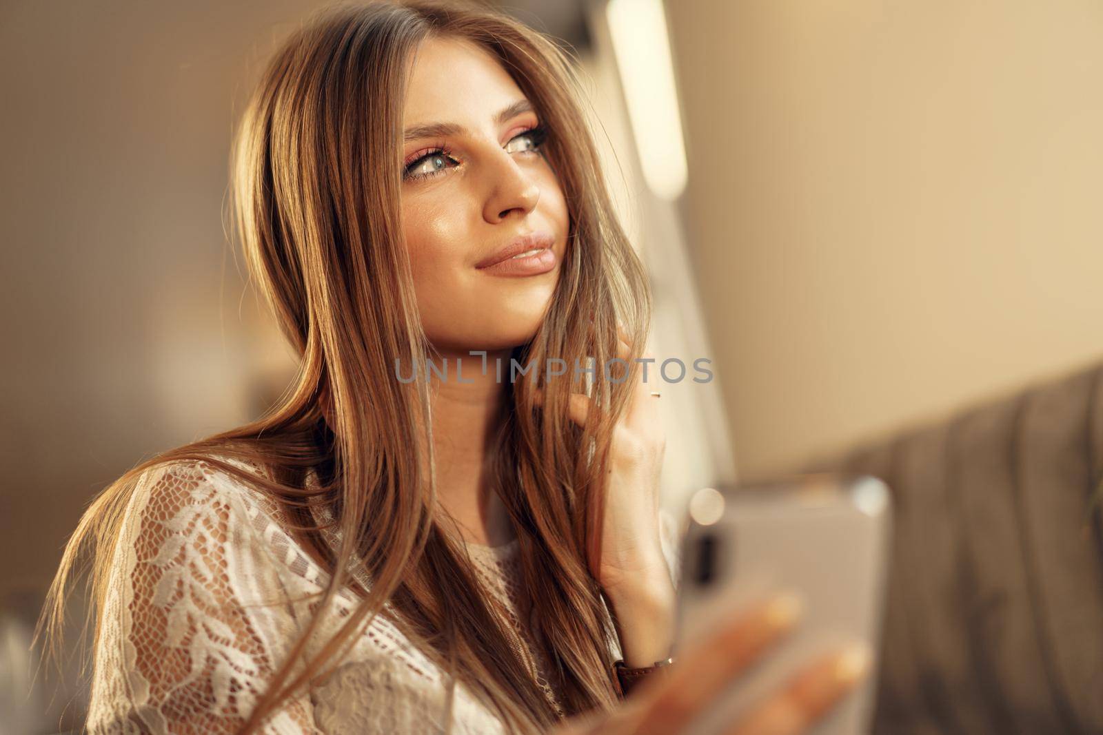 Happy young woman using her smartphone while sitting in cafeteria. Close up.