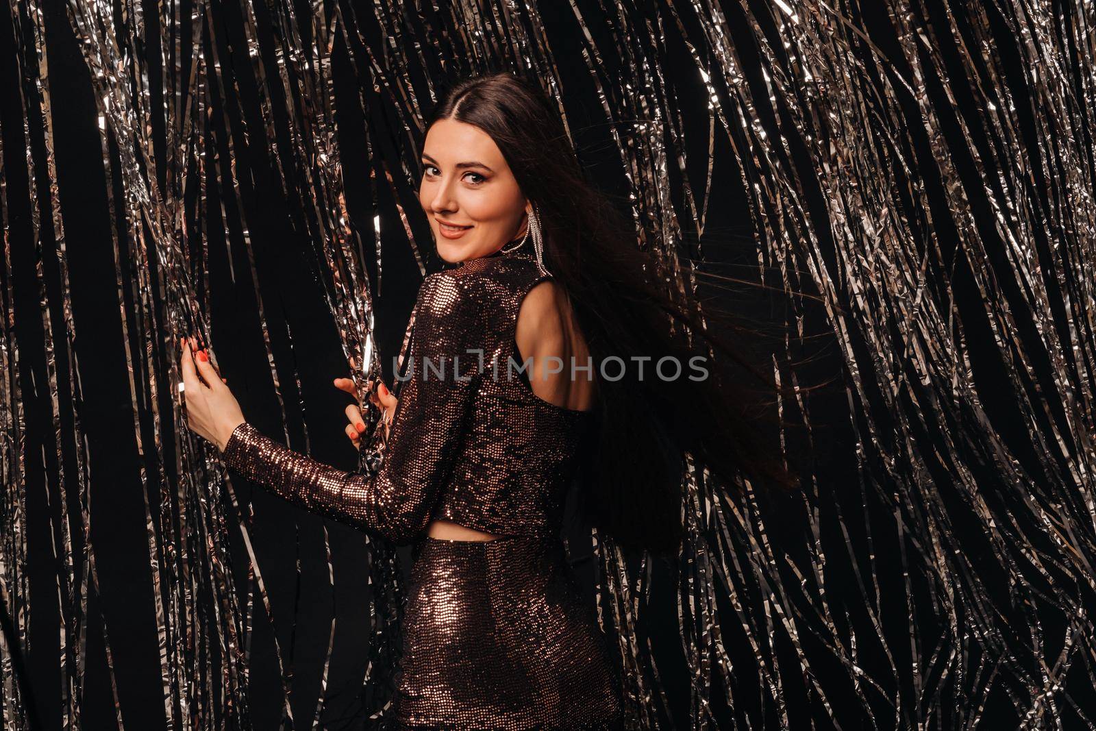 girl in a shiny dress on a silver background of New Year's rain.