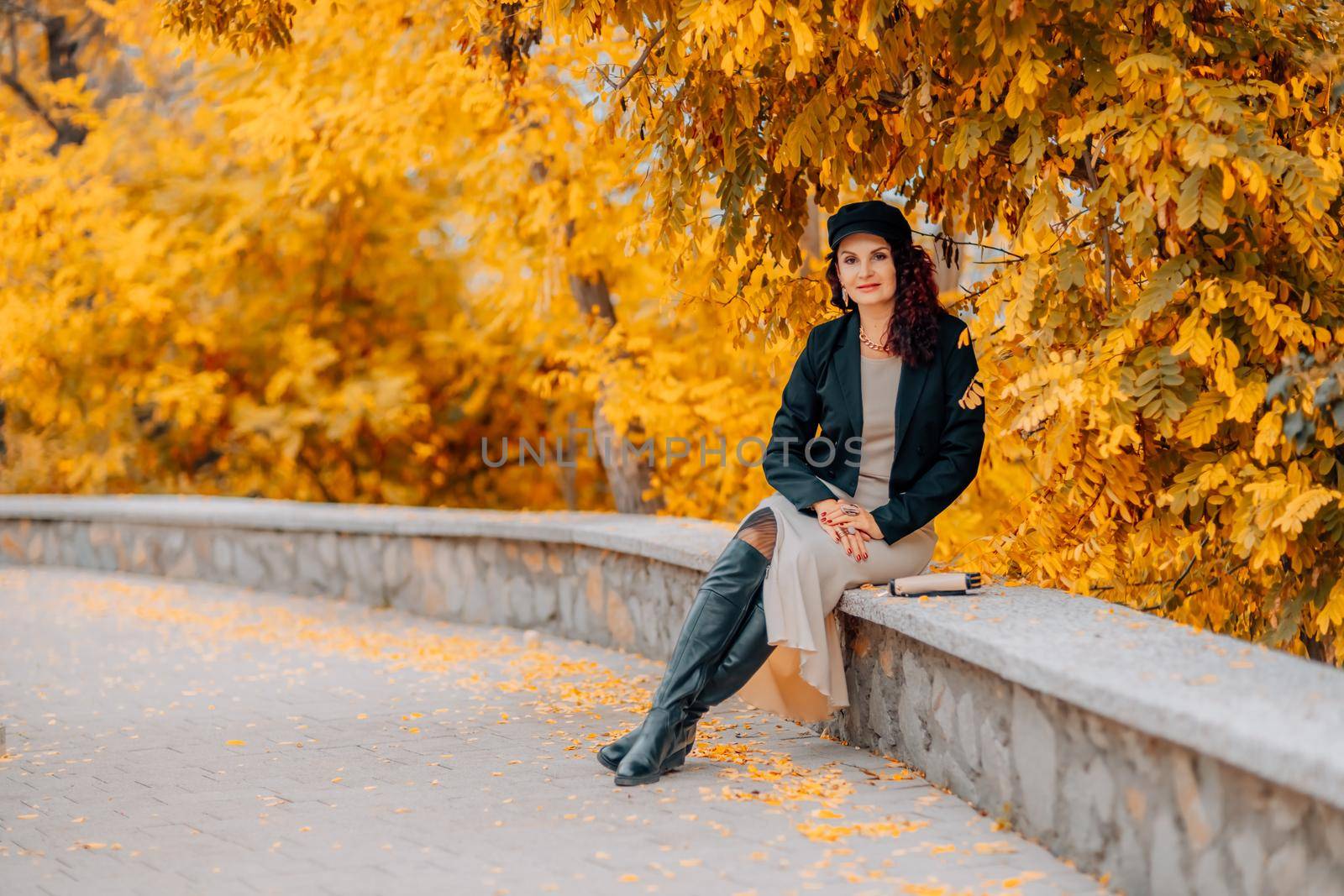 A young, beautiful girl sits on a background of yellow autumn foliage. Autumn Park. by Matiunina