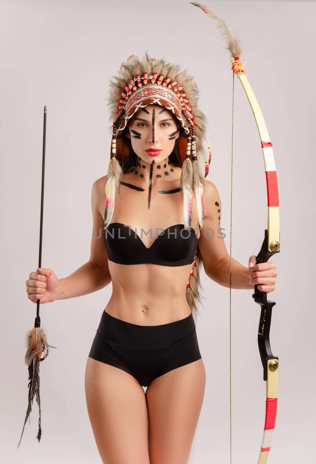 a woman in the image of indigenous peoples of America with a bow and arrow poses on a white background by Rotozey