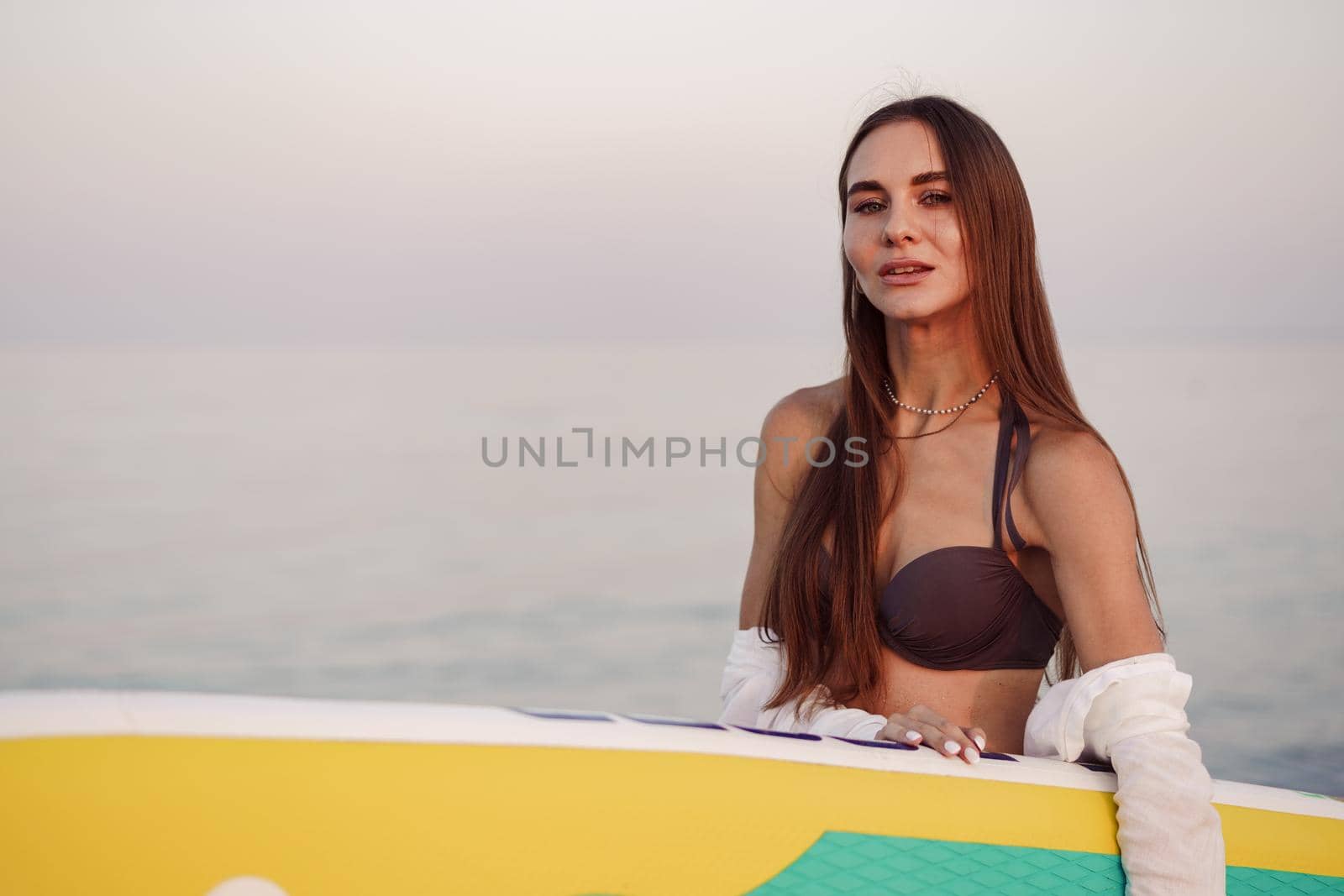 Young woman is carrying paddle board at the beach, close up