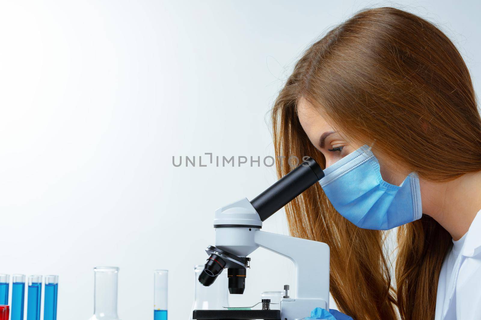 Woman scientist looking through a microscope in laboratory. Scientific research