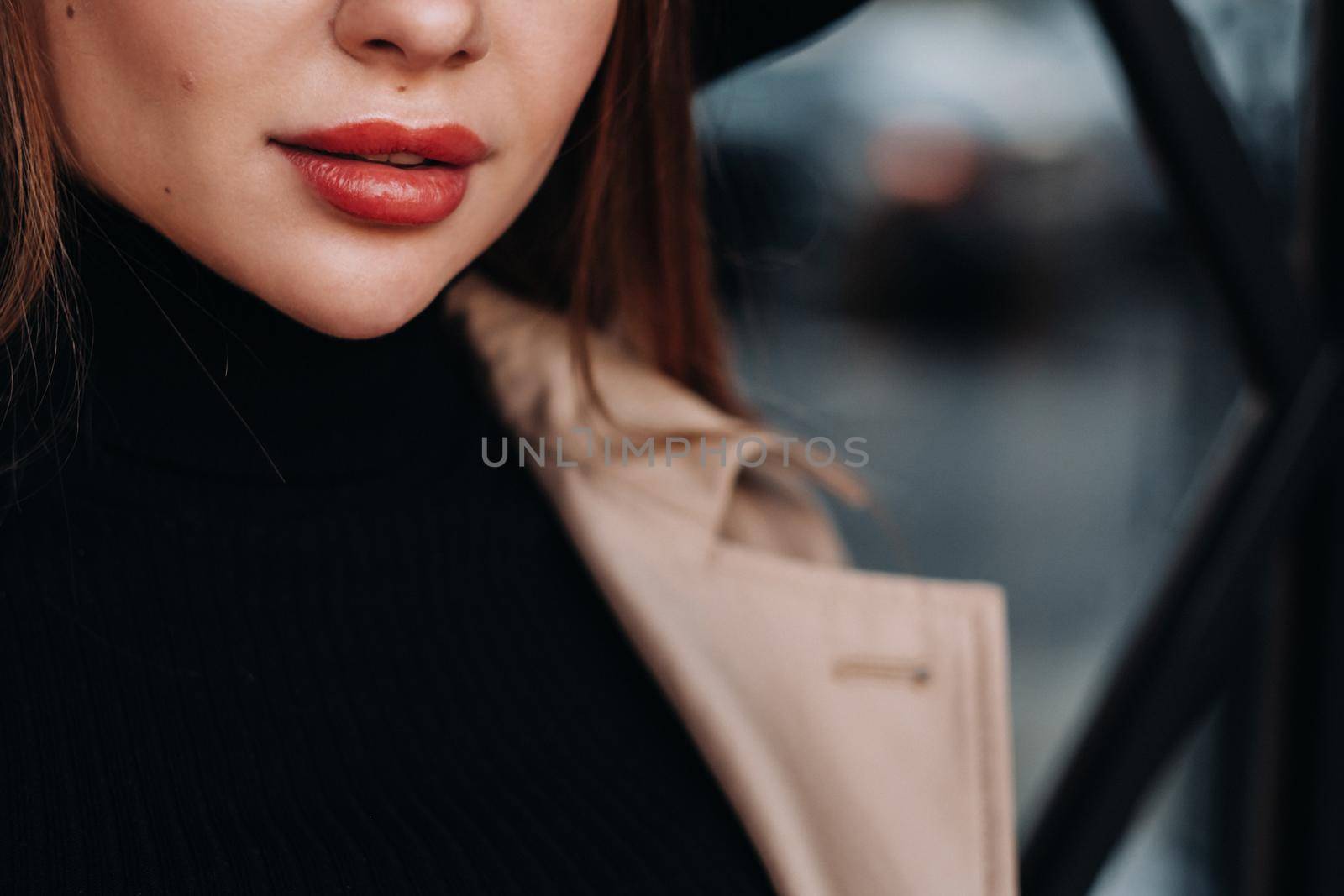 Close-up of the face and lips of a girl in a beige coat