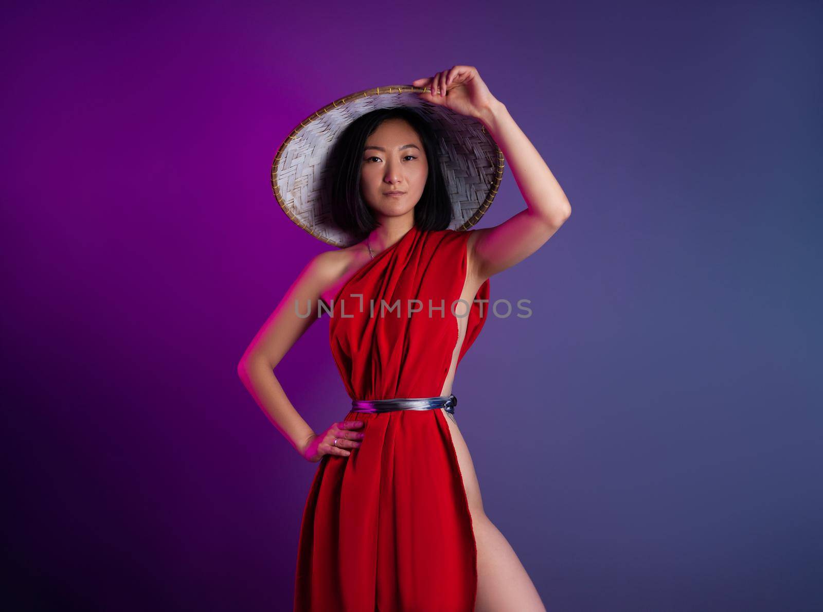 asian woman in red cape and asian hat posing on bright neon background by Rotozey