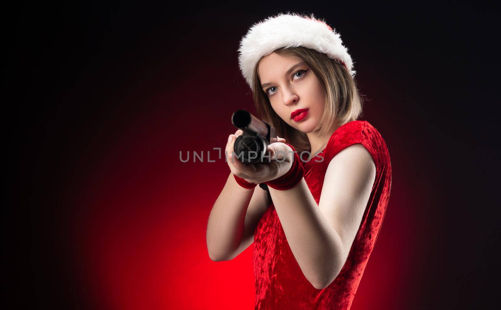 girl in a red bodysuit and a Santa Claus hat with a shotgun in her hands for Christmas