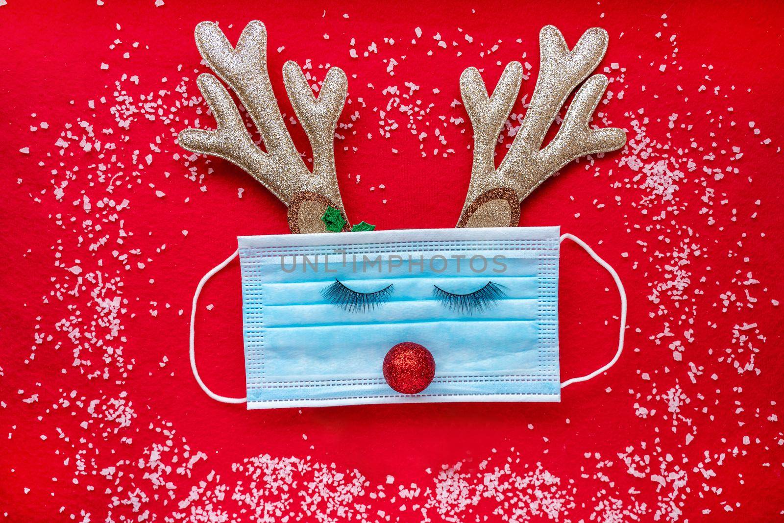 Medical mask with Christmas decoration on a red background. by Matiunina