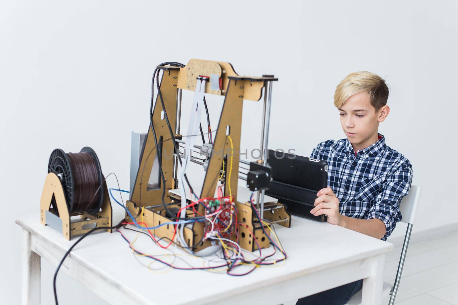 Education, children, technology concept - teen boy is printing on 3d printer