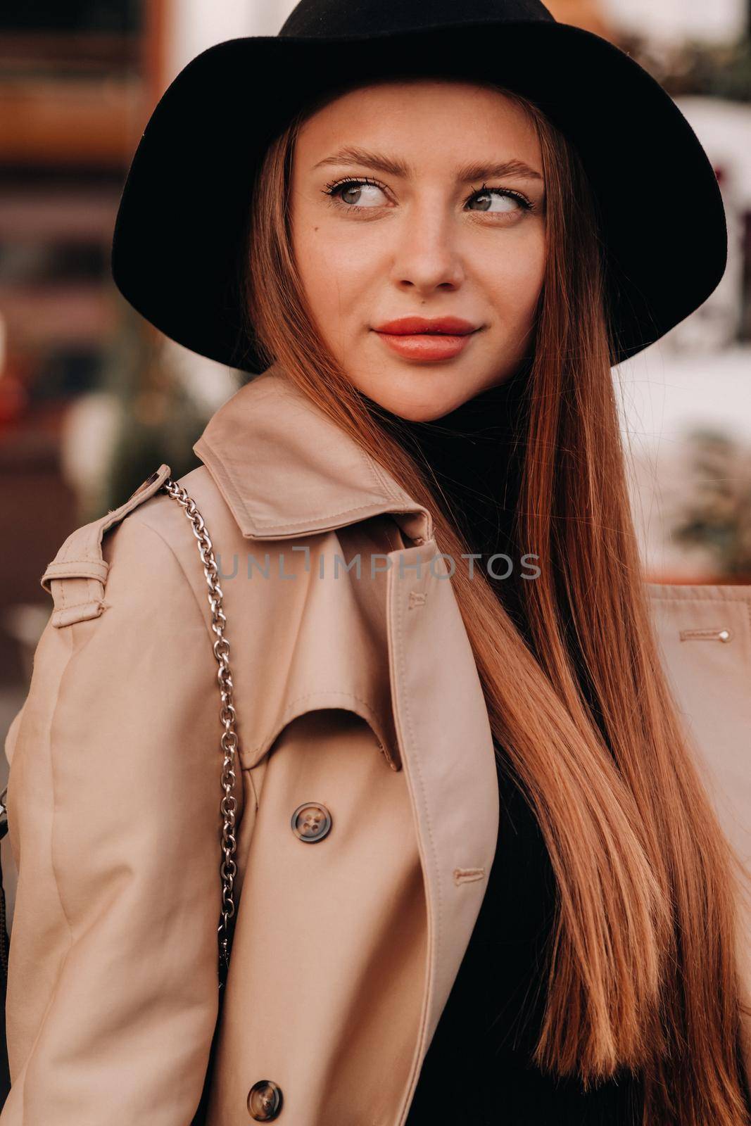 Portrait of a girl in a beige coat and black hat on a city street. Women's street fashion. Autumn clothing.Urban style.