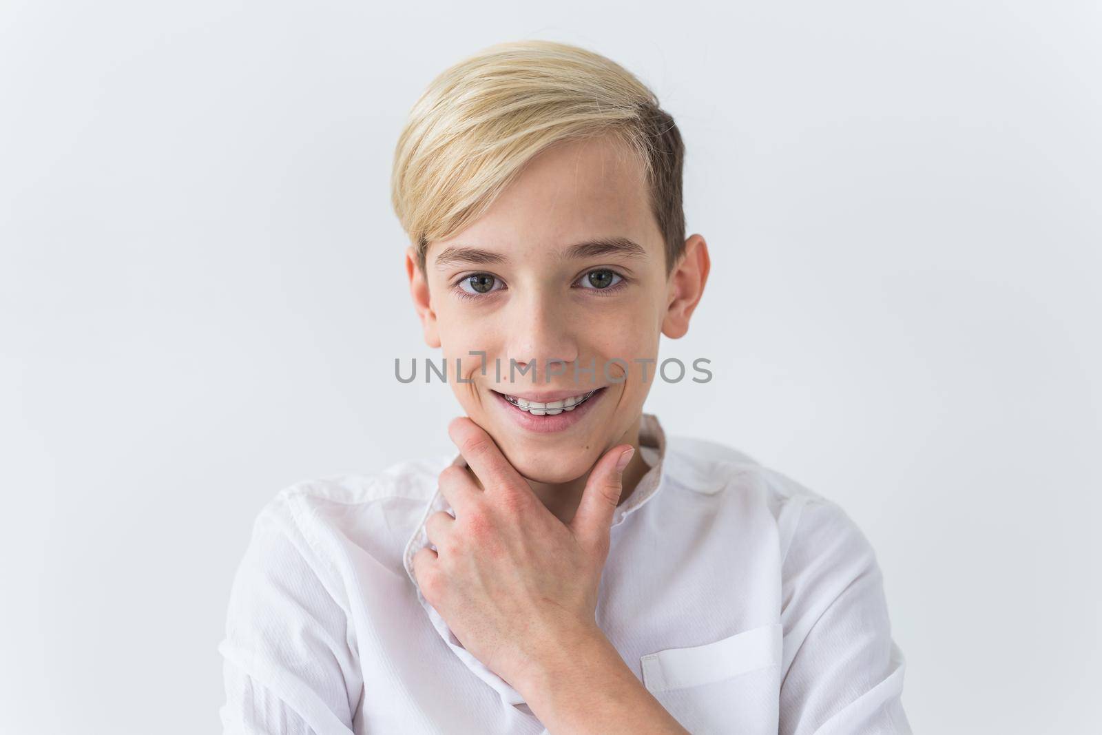Close-up of teen boy with braces on teeth smiling on white background. Dentistry and teenager concept. by Satura86