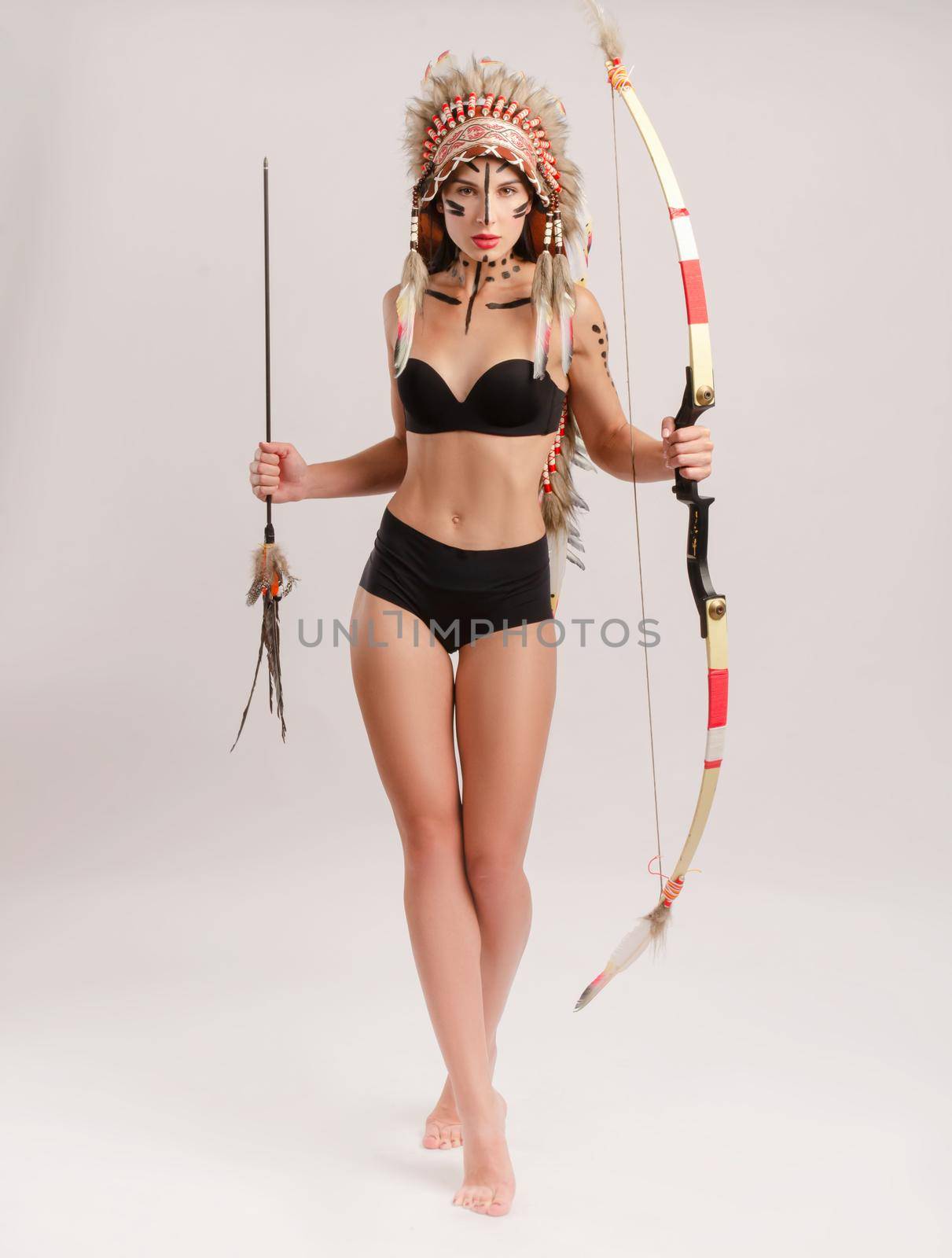 the woman in the image of indigenous peoples of America with a bow and arrow poses on a white background