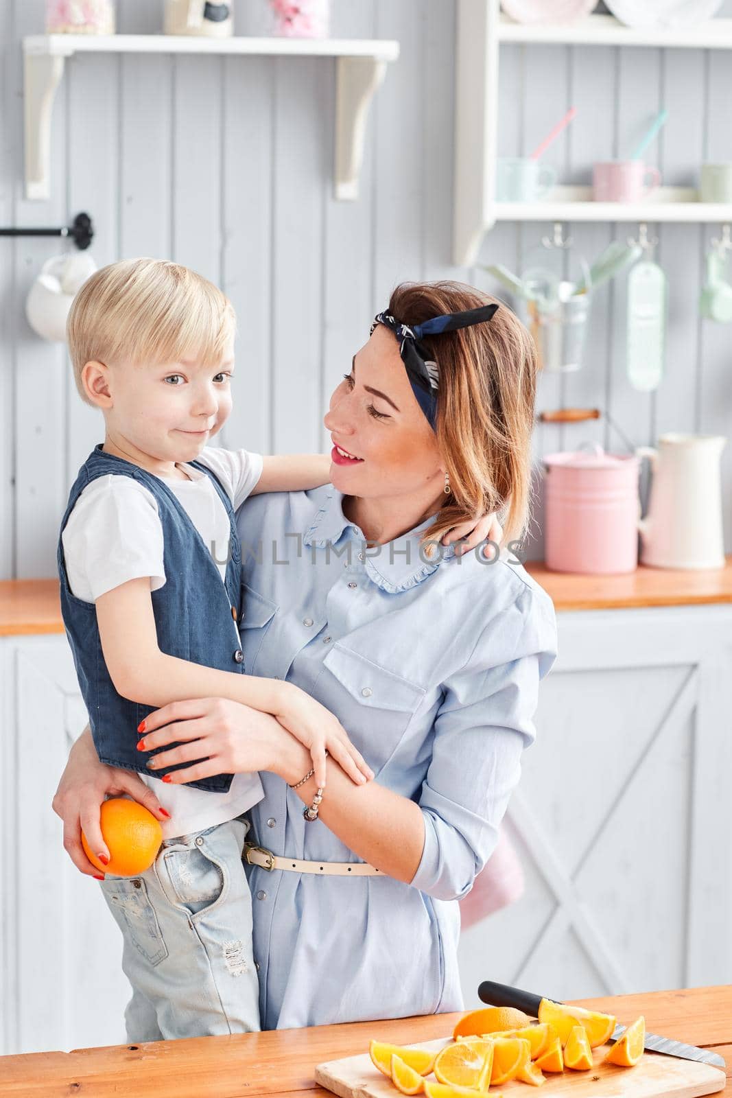Mother and son are smiling while having a breakfast in kitchen. Bright morning in the kitchen. Healthy Breakfast cereals and fresh fruit. by Malkovkosta