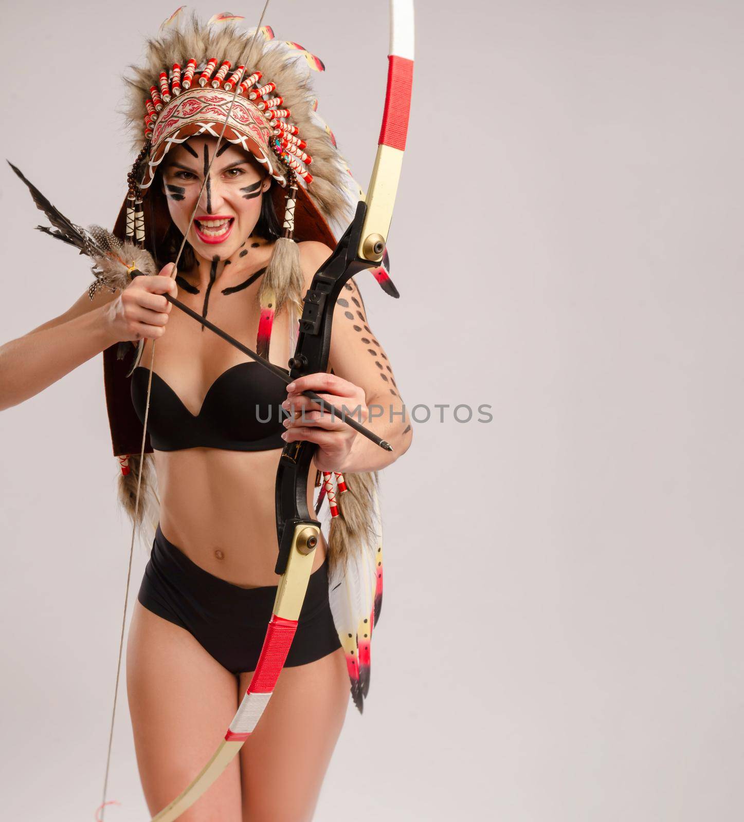 the woman in the image of indigenous peoples of America with a bow and arrow poses on a white background