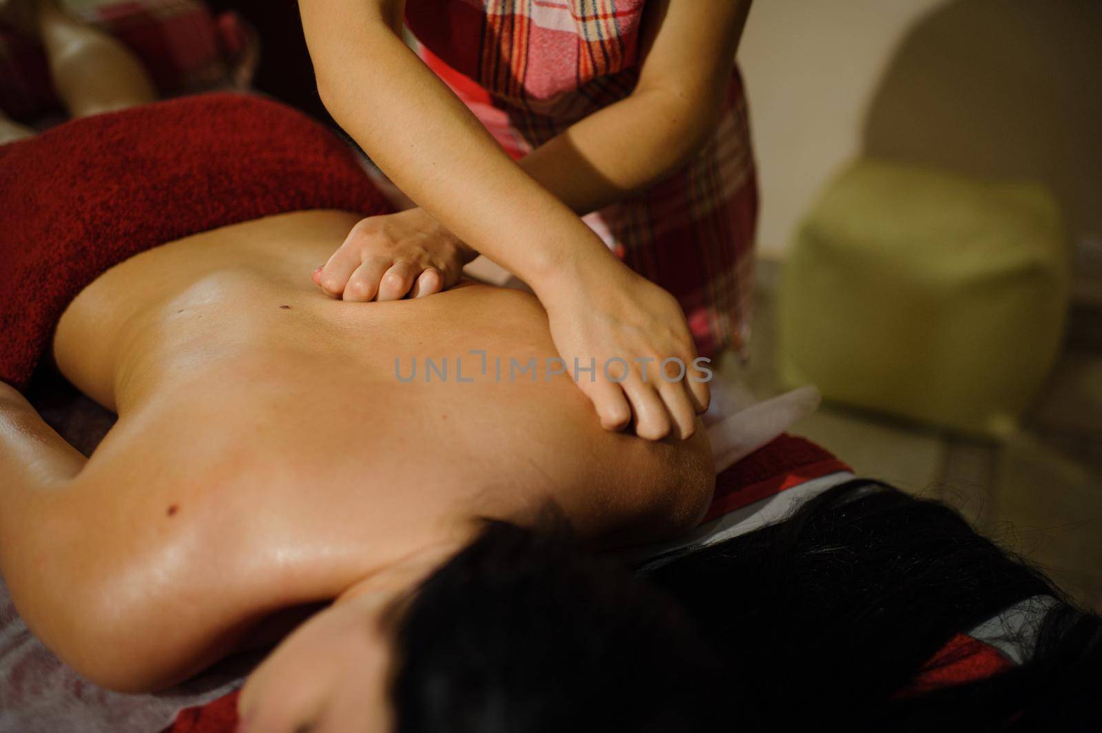 a woman gives a two-handed back massage to a girl lying in a Spa center.