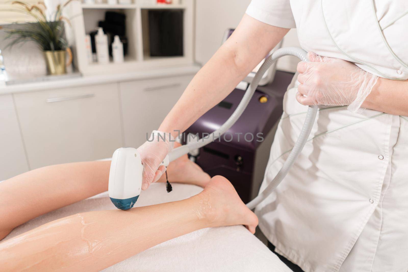 Doctor cosmetologist makes the procedure a young girl brunette. Laser epilation and cosmetology. Hair removal on ladies legs. at cosmetic beauty spa clinic