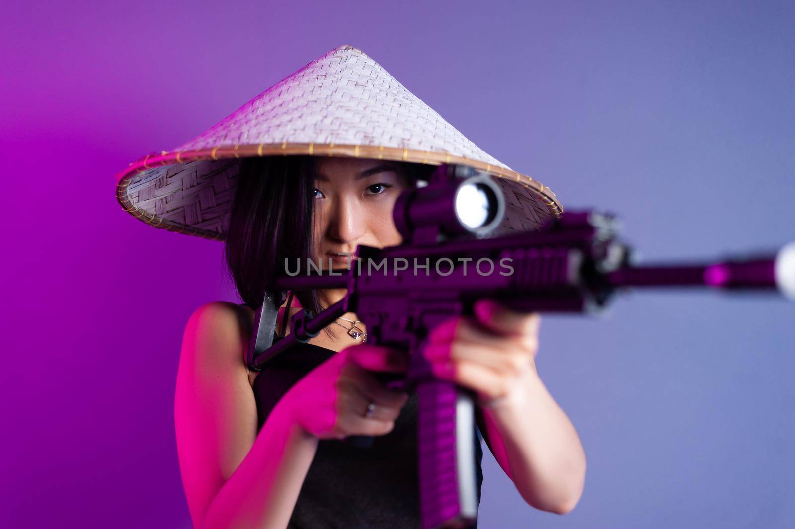 asian woman in an Asian hat with a machine gun aims