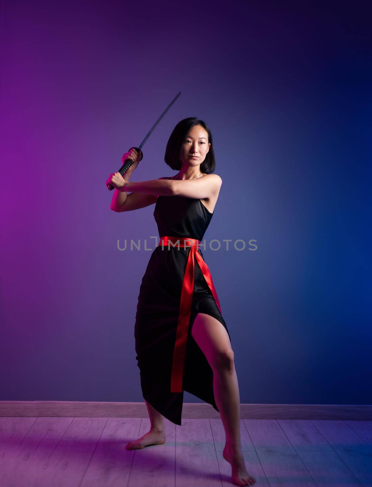 the slender Asian woman in a black dress with a katana in her hand image of a samurai on a neon background