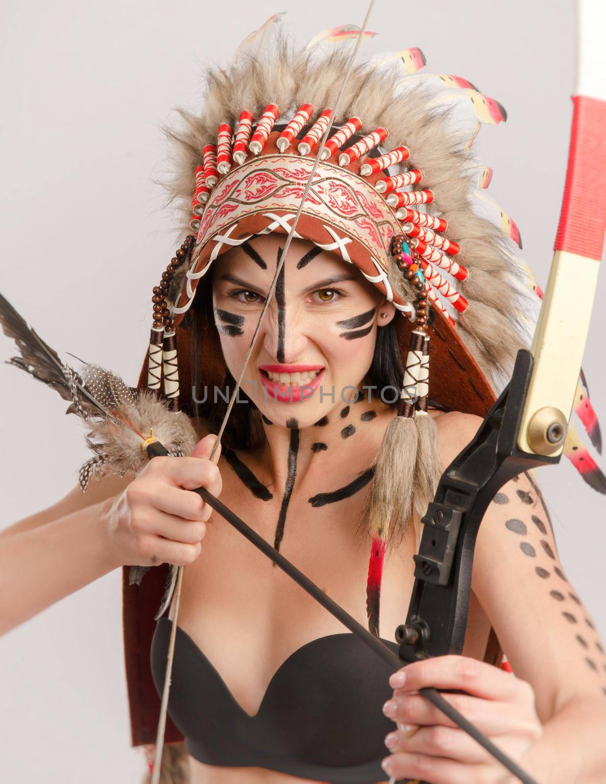 a woman in the image of indigenous peoples of America with a bow and arrow poses on a white background by Rotozey