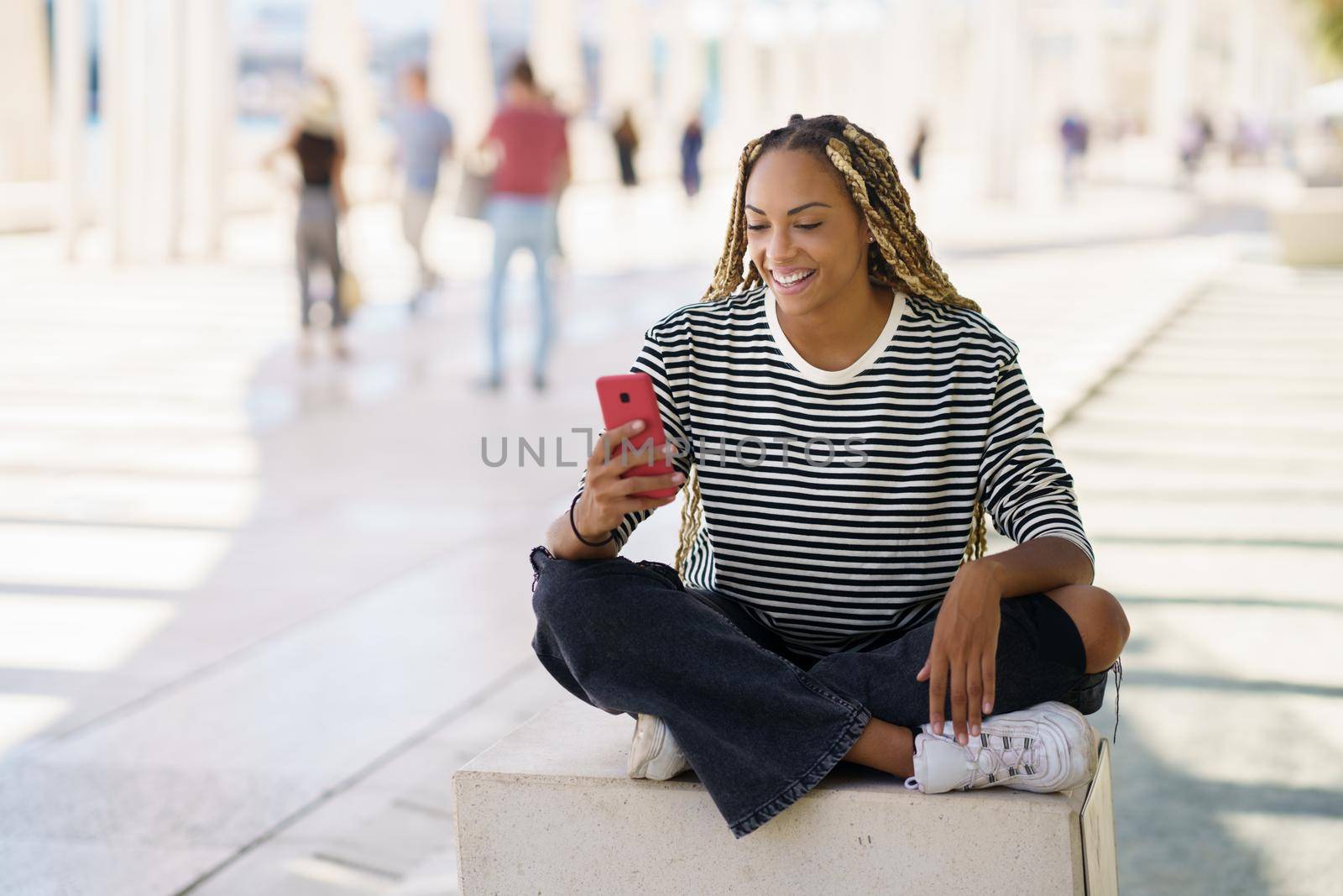 Hapy black woman using a smartphone, wearing her hair in braids. Typical African hairstyle.