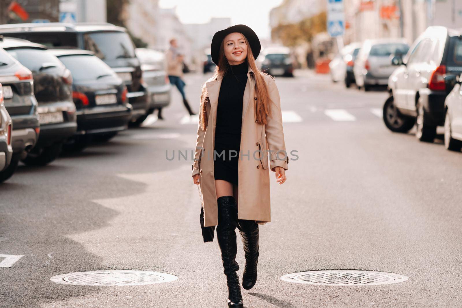 Stylish young woman in a beige coat in a black hat on a city street. Women's street fashion. Autumn clothing.Urban style by Lobachad