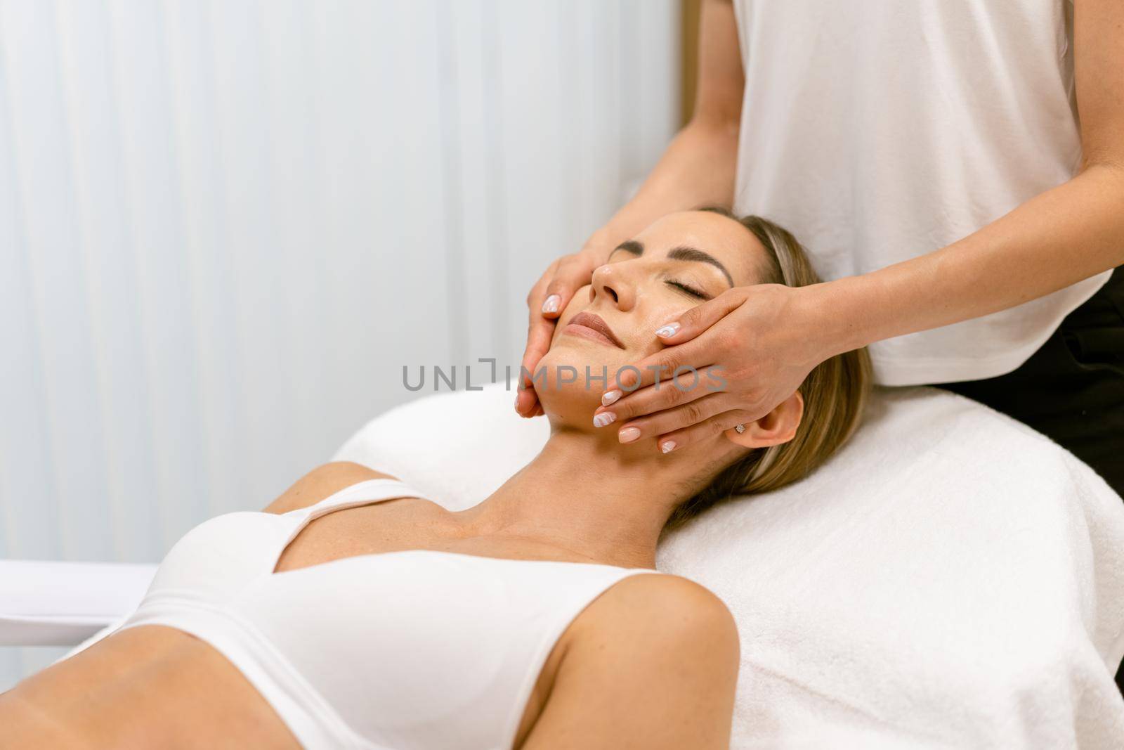 Middle-aged woman having a head massage in a beauty salon. Body care treatment in a beauty centre.