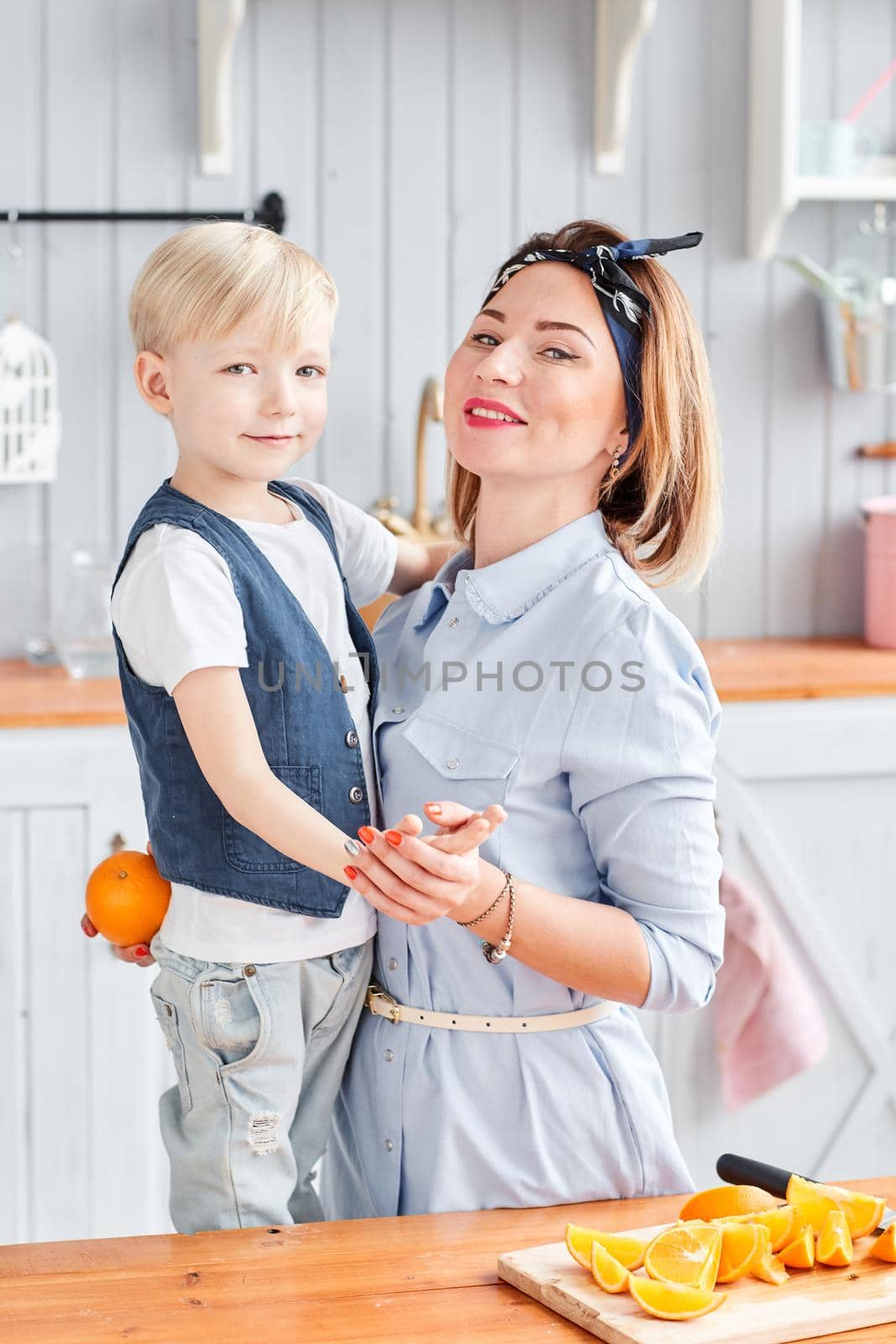Mother and son are smiling while having a breakfast in kitchen. Bright morning in the kitchen. Healthy Breakfast cereals and fresh fruit