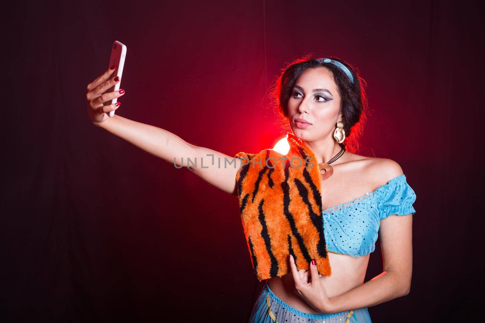 Girl doing selfie with tiger skin, crazy photos. Don't eco friendly lifestyle. Young woman takes pictures of herself in the phone. Life in social networks, narcissism, modern personality. Personality disorder. by Satura86