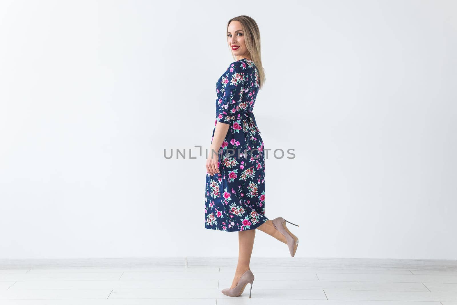 Fashionable young blonde woman in beautiful summer dress posing at white studio with copy space. by Satura86