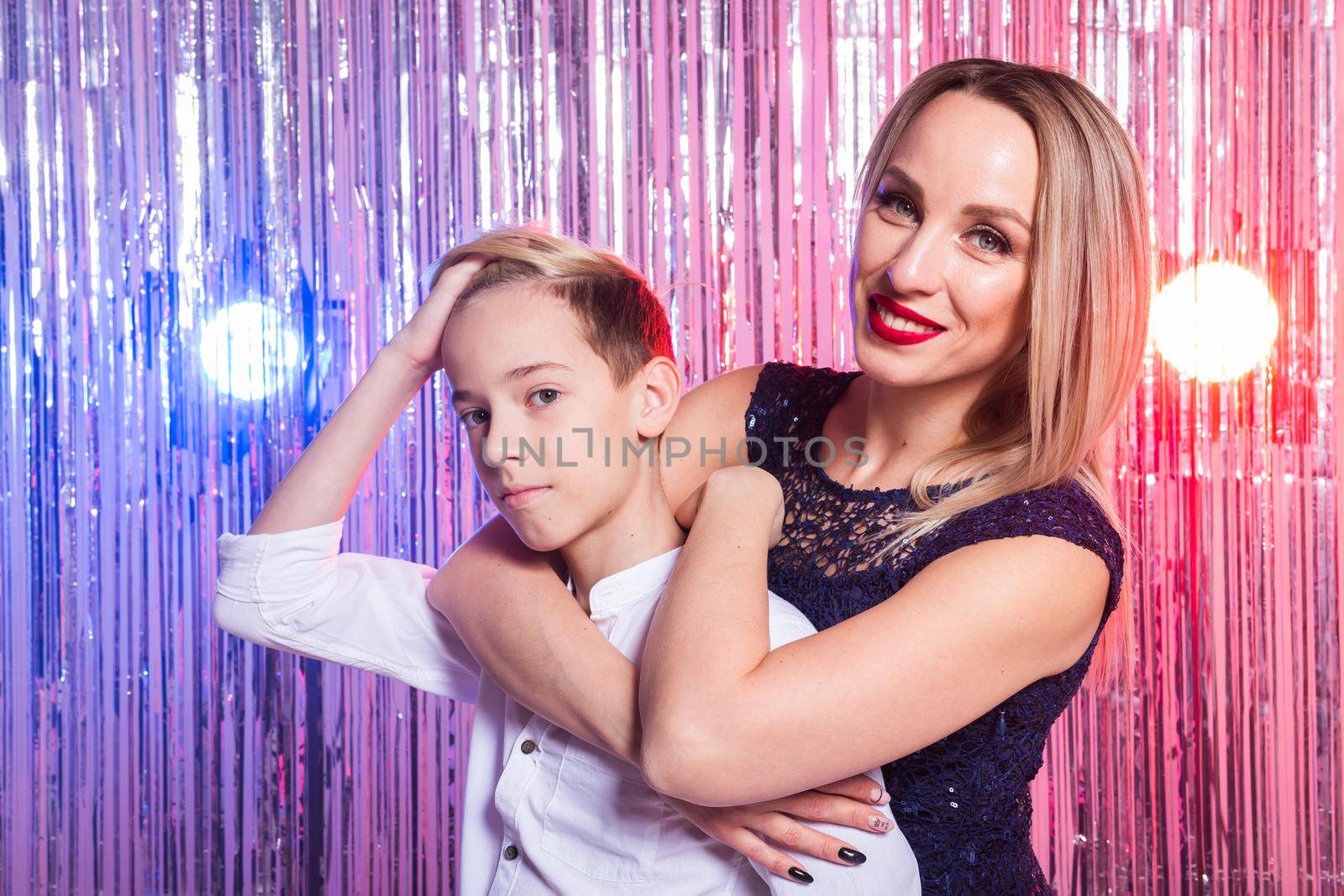 Mothers day, children and family concept - teen boy hugging his mom on shiny party background. by Satura86