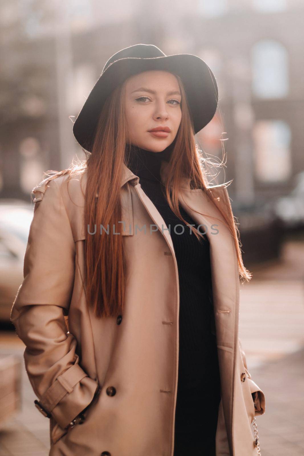 Stylish young woman in a beige coat in a black hat on a city street. Women's street fashion. Autumn clothing.Urban style.