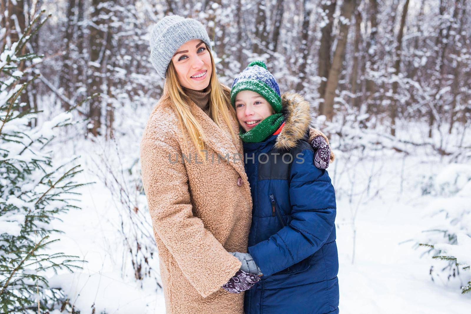 Portrait of happy mother with child son in winter outdoors. Snowy park. Single parent. by Satura86