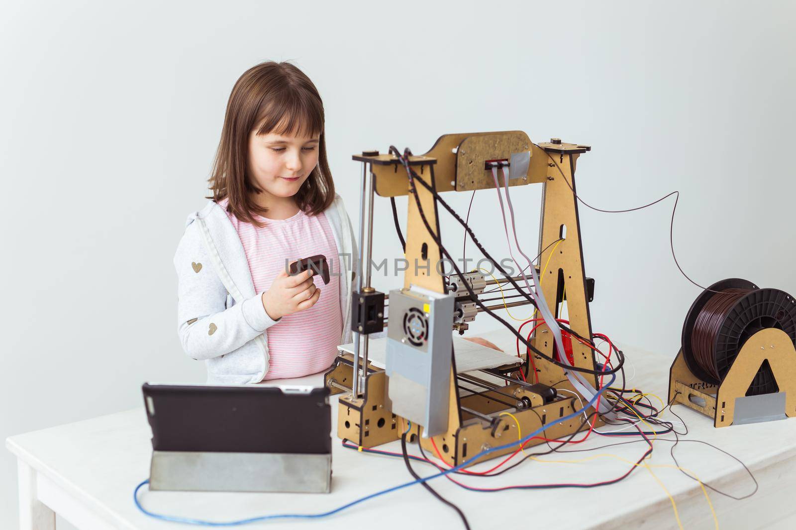 Cute girl with 3d printed shutter shades is watching her 3d printer as it prints her 3d model. by Satura86