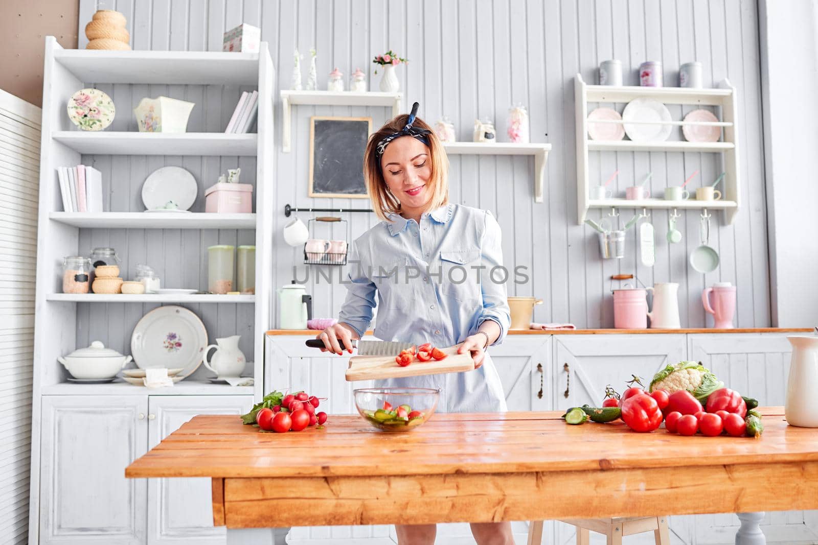 Beautiful young woman is preparing vegetable salad in the kitchen. Healthy Food. Cooking at home. Dieting Concept
