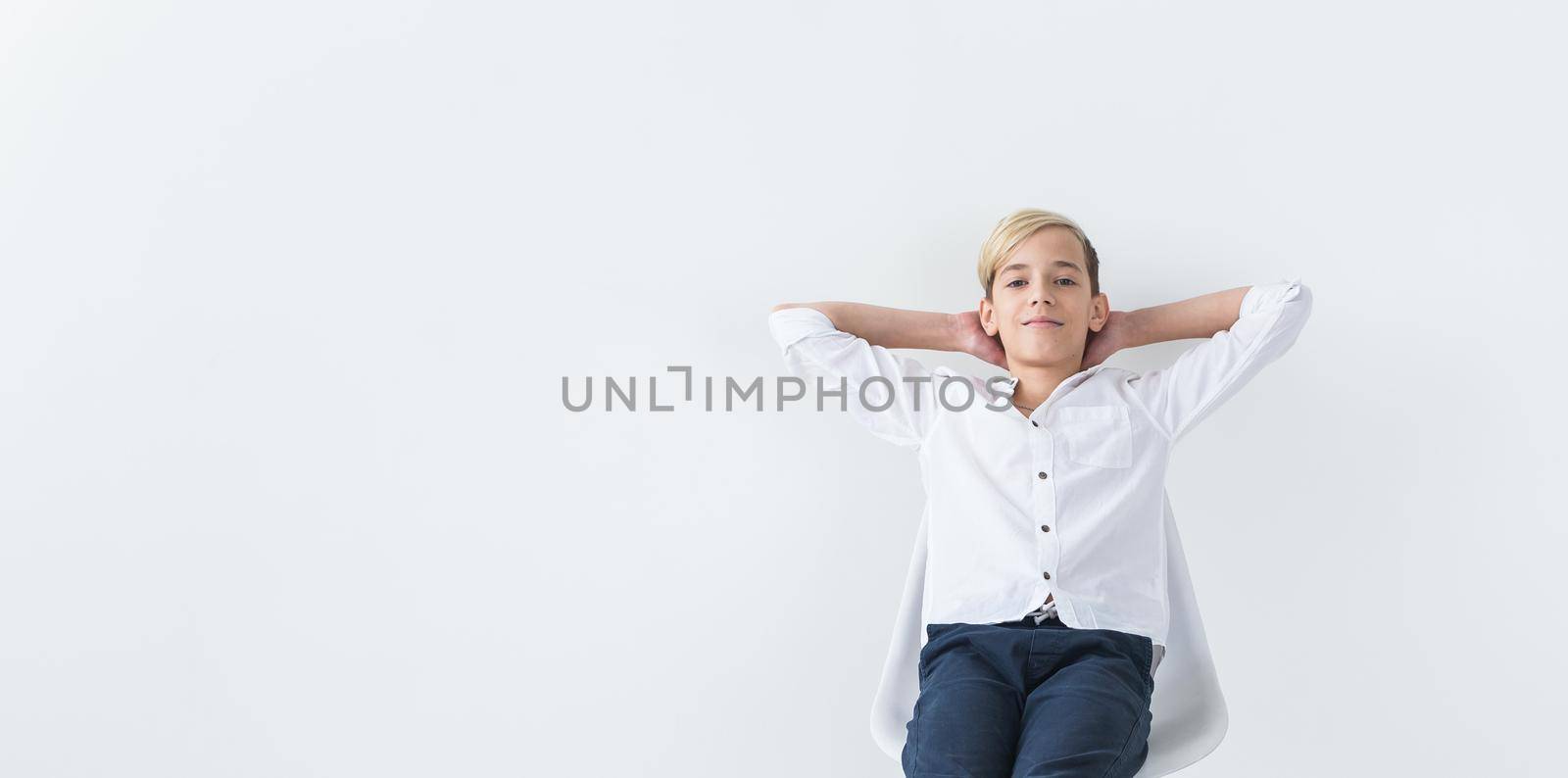 Solitude, loneliness and boredom concept - Bored teen student sitting in a school chair isolated on white background with copy space. by Satura86