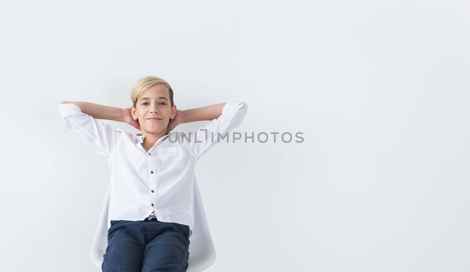 Solitude, loneliness and boredom concept - Bored teen student sitting in a school chair isolated on white background with copy space. by Satura86