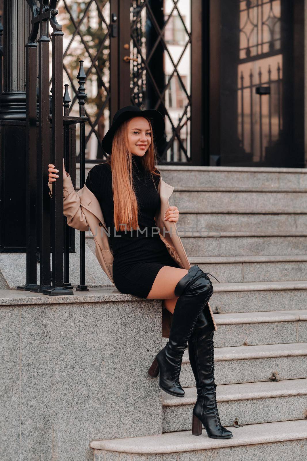 Stylish young woman in a beige coat in a black hat on a city street. Women's street fashion. Autumn clothing.Urban style by Lobachad