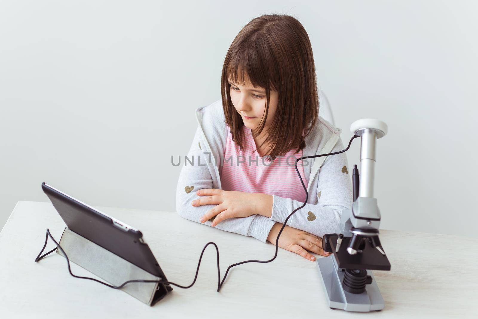 Schoolgirl using microscope in science class. Technologies, lessons and children concept. by Satura86