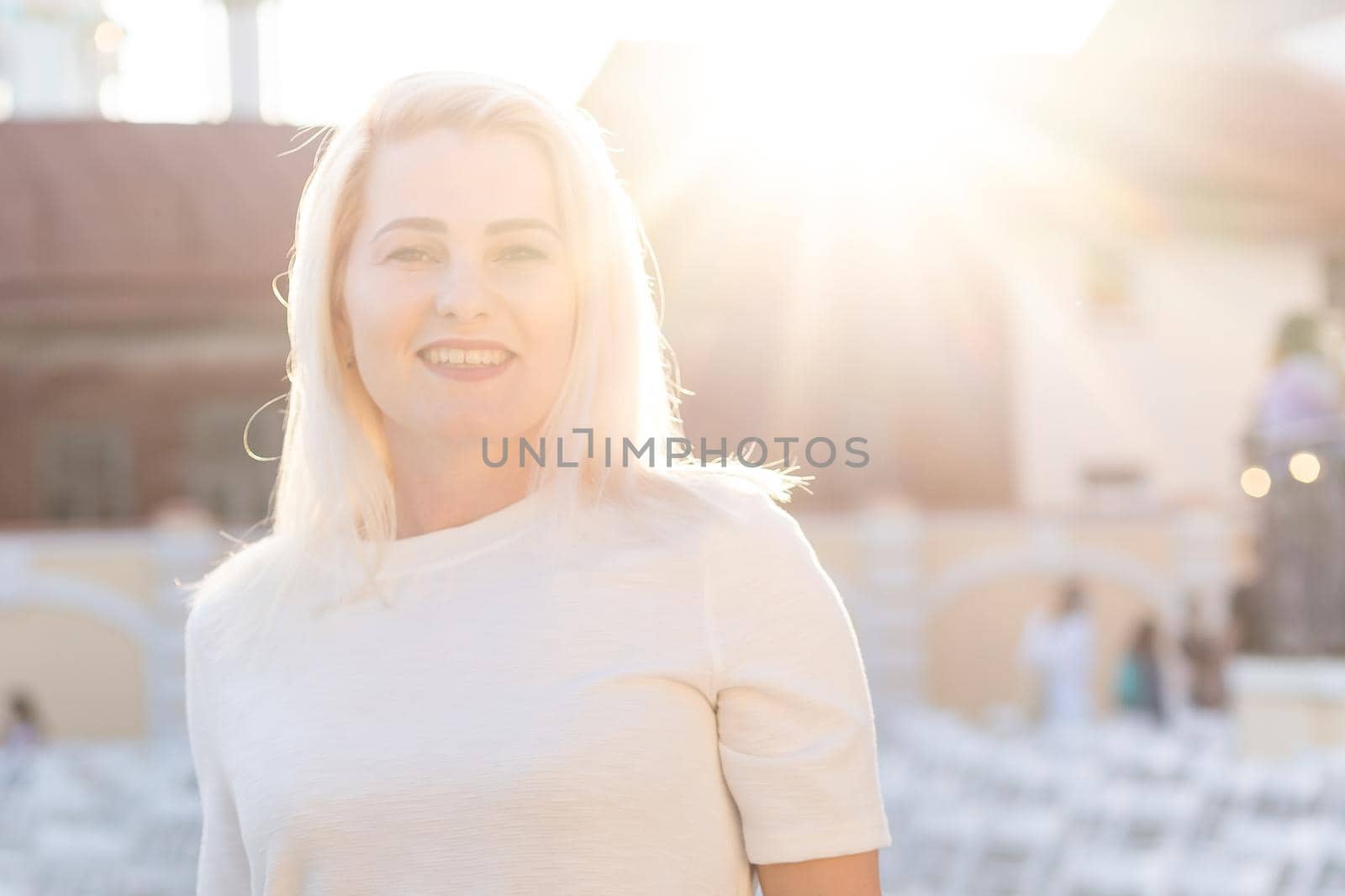 attractive woman dressed in white dress in summer open air theater on chair alone, spring street style fashion trend, social distancing