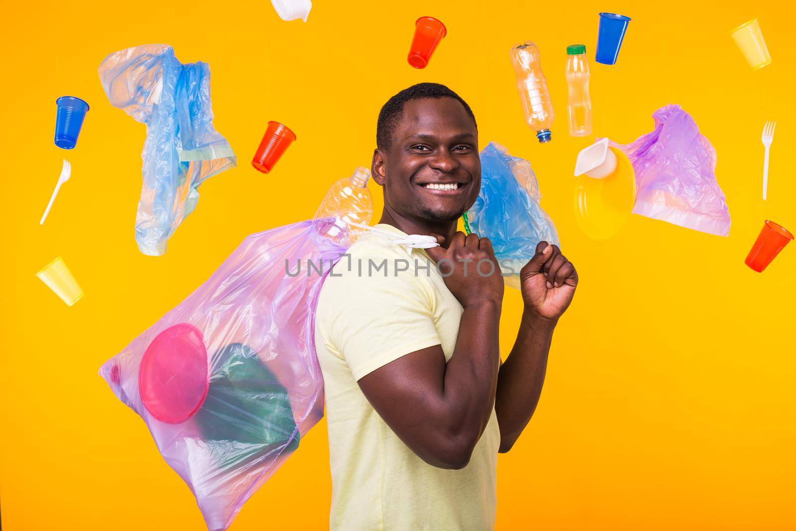 Problem of trash, plastic recycling, pollution and environmental concept - confused man carrying garbage bag on yellow background.