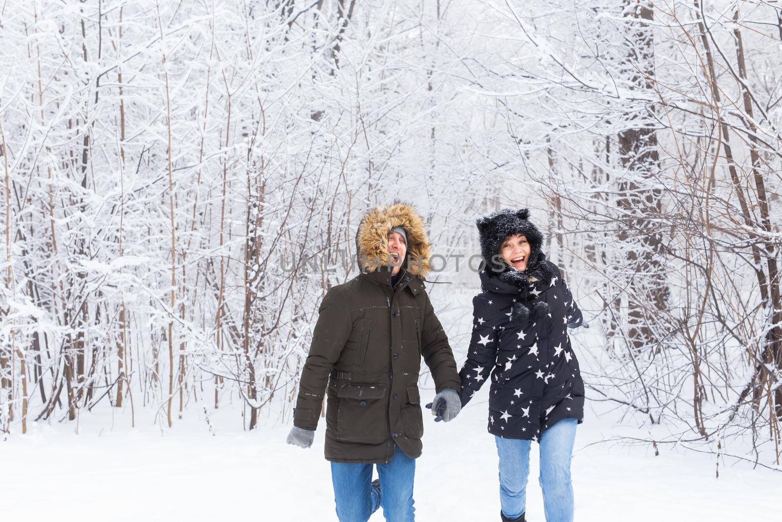 Happy couple walking through a snowy forest in winter.