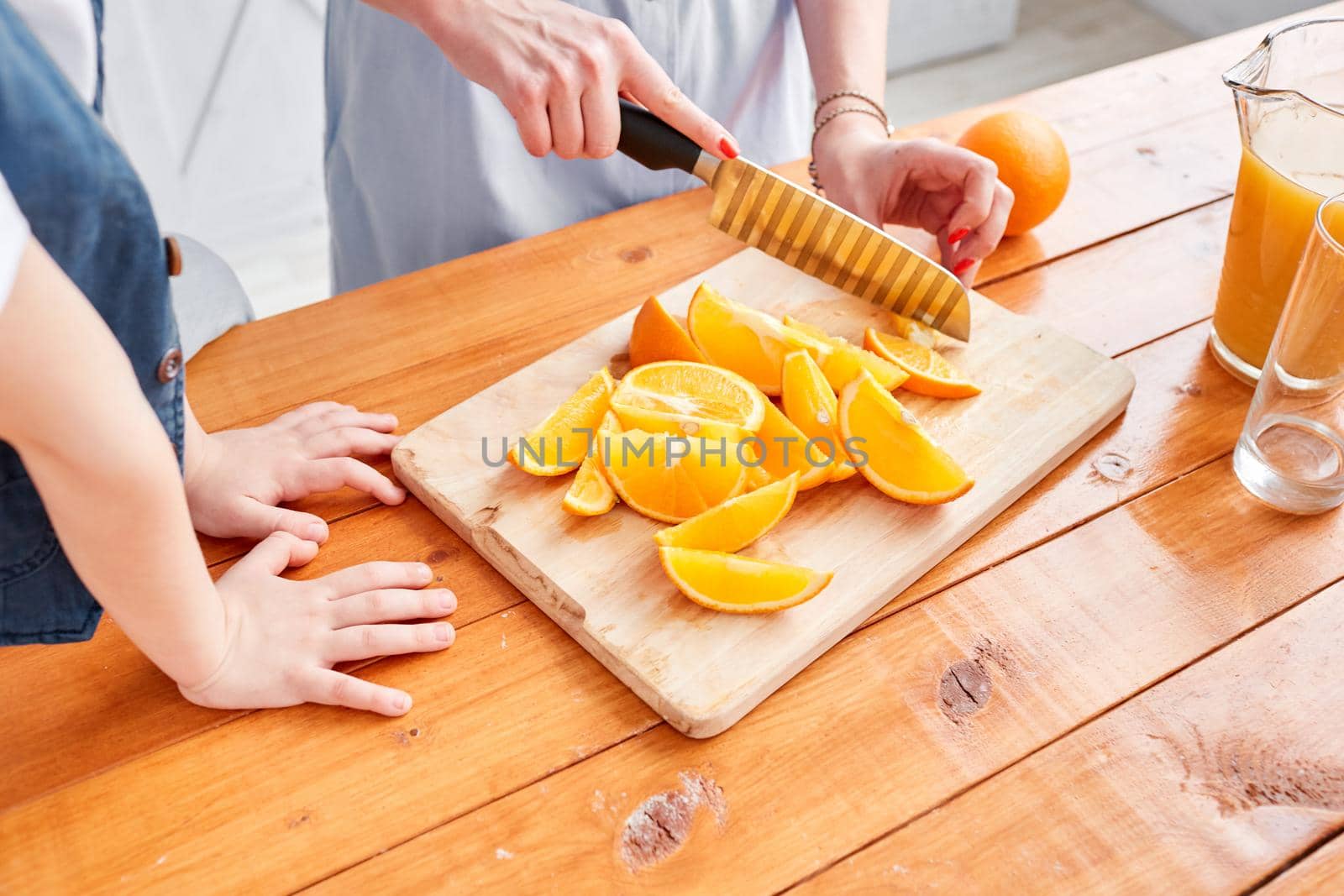 Closeup of a sliced orange. Healthy food, fresh fruit, juicy oranges. Mother and son are smiling while having a breakfast in kitchen. Bright morning in the kitchen. by Malkovkosta