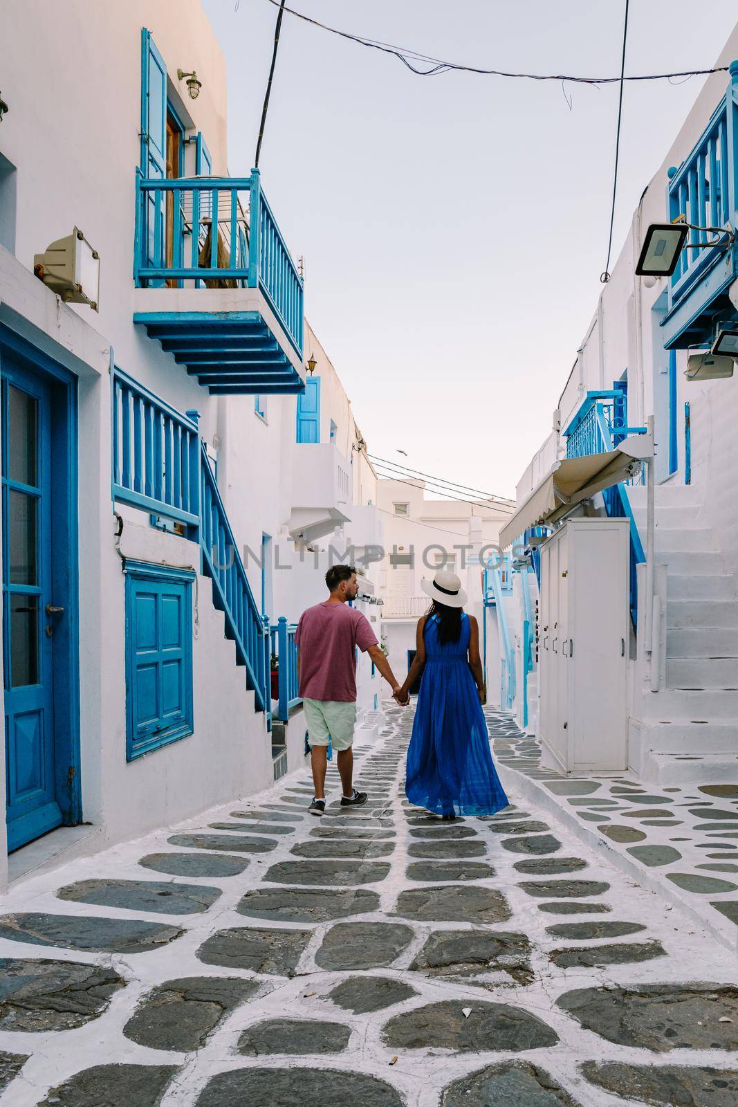 Mykonos Greece, Young man and woman in dress at the Streets of old town Mikonos during vacation in Greece, Little Venice Mykonos Greece by fokkebok