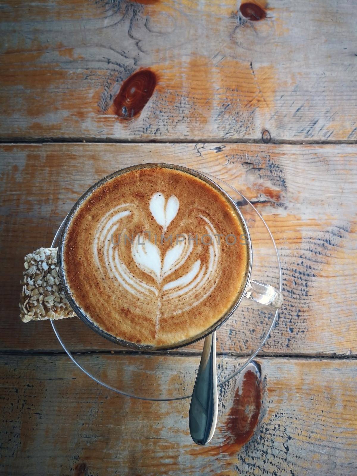 Coffee in glass cup with cookies on wooden table in cafe with lighting background