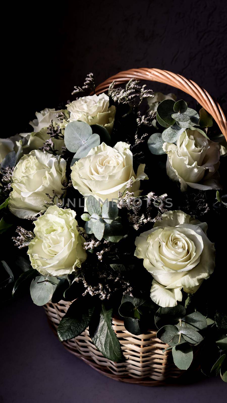 Bouquet of beautiful white roses in a wicker basket on a dark background. Perfect for greeting card by Olayola