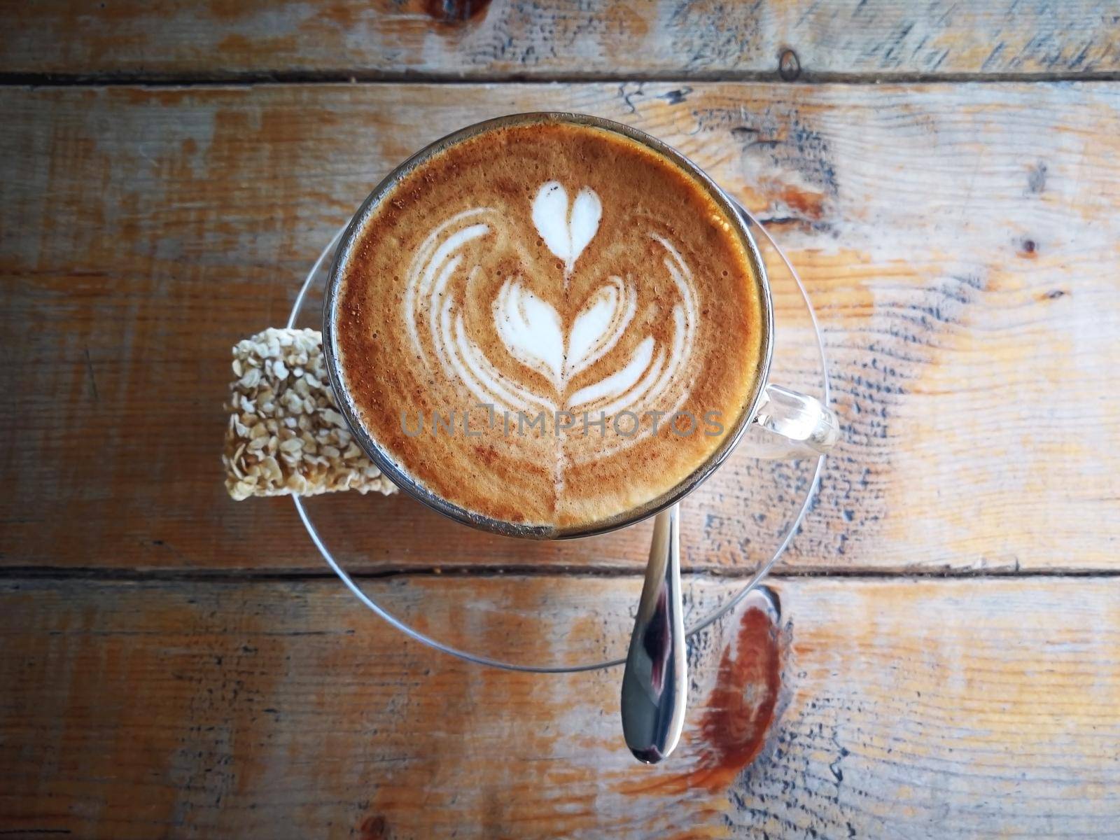 Coffee in glass cup with cookies on wooden table in cafe with lighting background