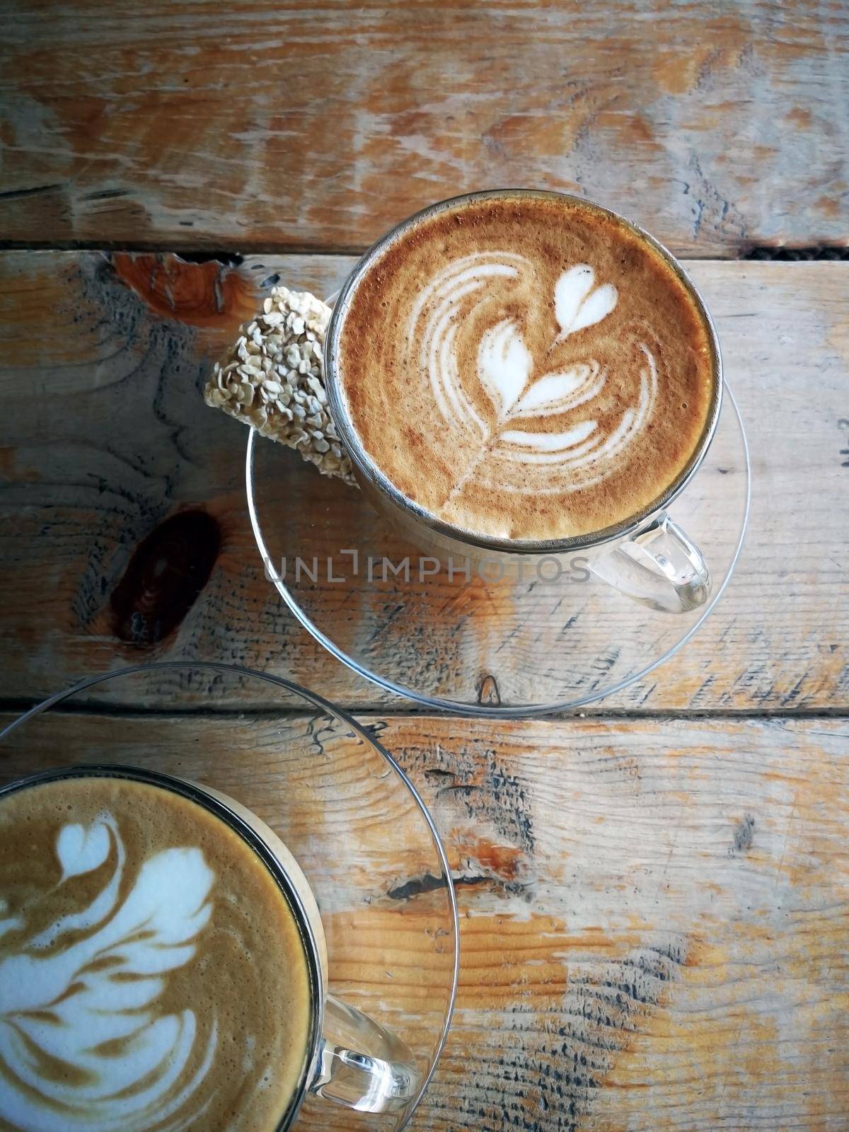 Coffee in glass cup with cookies on wooden table in cafe with lighting background