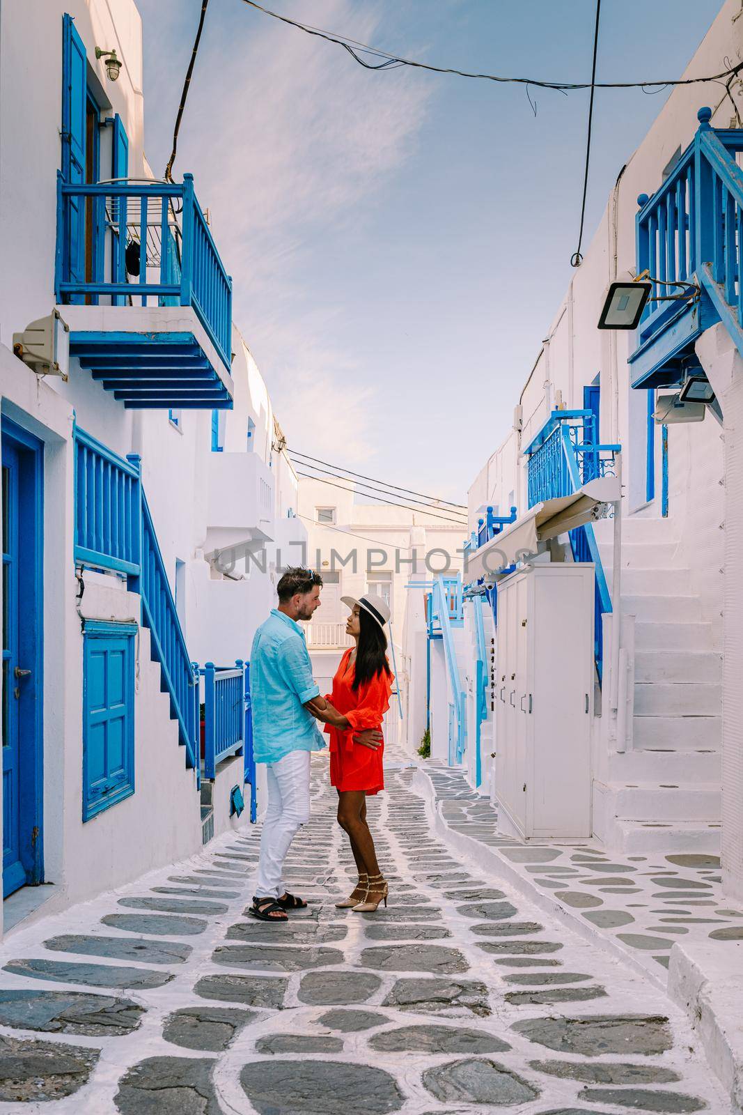 Mykonos Greece, Young man and woman in dress at the Streets of old town Mikonos during vacation in Greece, Little Venice Mykonos Greece by fokkebok