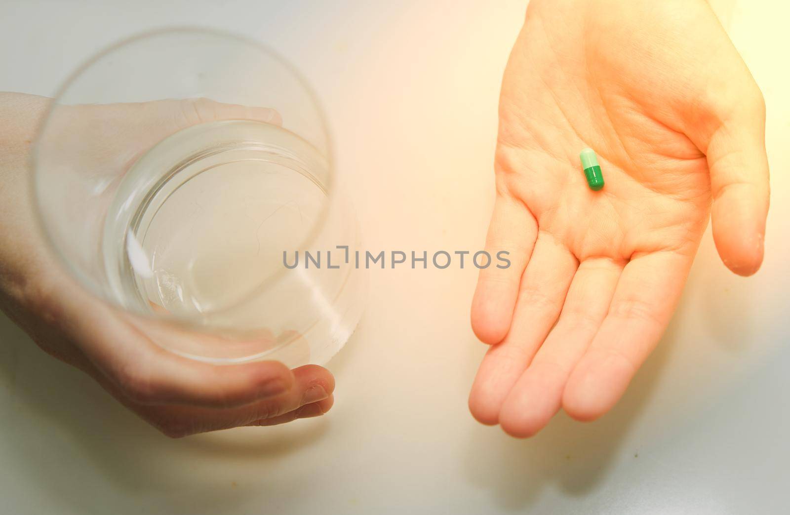 woman hand hold pill supplement antioxidant vitamin mineral capsule with water glass before take medicine capsule for health care